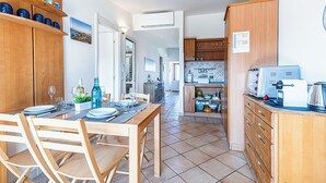 Una cucina moderna con mobili in legno, una zona pranzo con tavolo apparecchiato per quattro persone e un bancone cucina con elettrodomestici.
