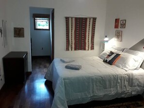 Un dormitorio con cama, mesita de noche, lámpara y ventana.