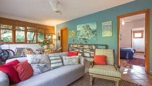 A cozy living room with a sofa, armchairs, a bookshelf, and a bicycle. - Suite in a chalet on the dam (Praia Azul São Paulo)