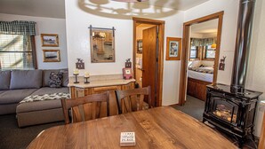 Un salon chaleureux avec une table à manger en bois, un canapé et un poêle à bois.