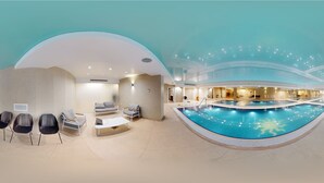 A modern indoor pool area with seating and a reception desk.