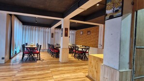 A restaurant with wooden flooring, red cushioned chairs, and a wooden counter. - White Villa (Shimla)