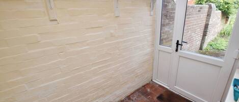 A narrow hallway with a white door and a window.