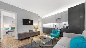 A modern living room with a glass coffee table, a teal armchair, and a grey sofa. - Modern London Nell Gwynn House Apartment (London)