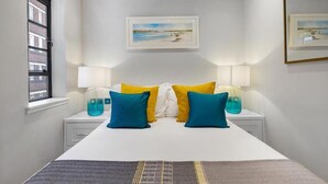 A bedroom with a bed, two bedside tables with lamps, a window, and a framed picture on the wall. - Modern London Nell Gwynn House Apartment (London)