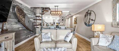 A spacious living area with a modern staircase, a glass coffee table, and a comfortable seating arrangement.