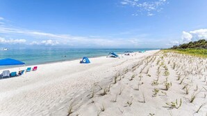 A beach with tents, chairs, and a clear sky. - Aldea 18 Beachfront Condo in Belleair Beach (Belleair Beach)