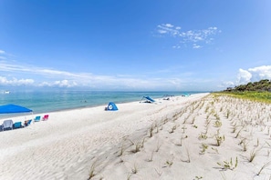 A beach with tents, chairs, and a clear sky.