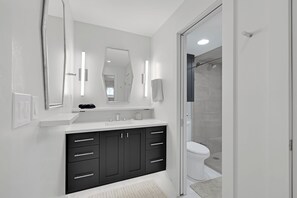 A modern bathroom with a white vanity, dark cabinets, a large mirror, and a glass shower enclosure. - Full Renovated 2BR in Dillon! (Dillon)