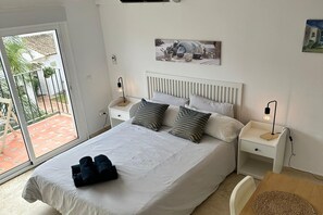 A neatly arranged bedroom with a bed, pillows, a bedside table, a lamp, and a view of the outside. - Studio in Estepona Near Sandy Beach (Estepona)