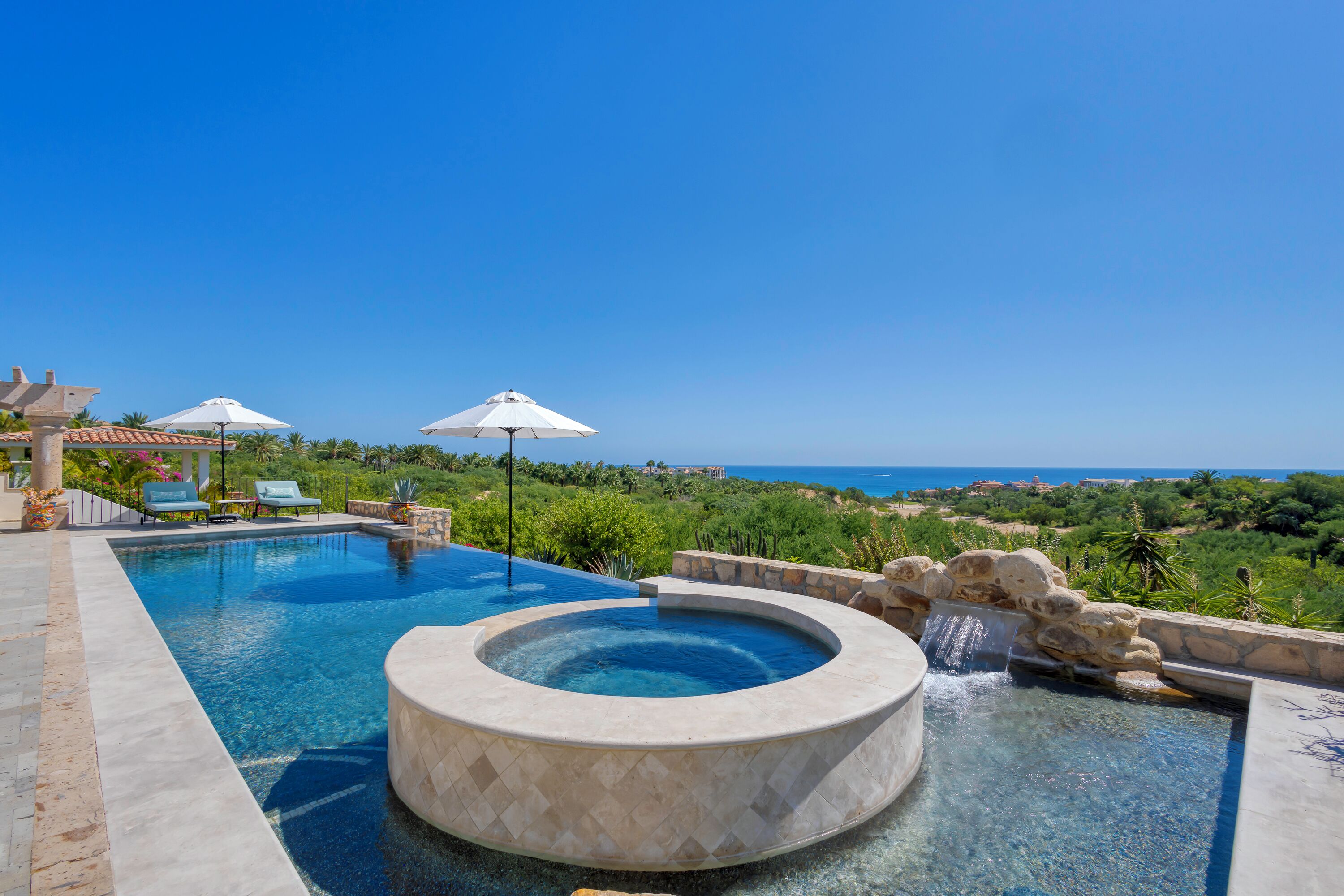 Ein Pool mit Whirlpool, Liegestühlen und Sonnenschirmen.