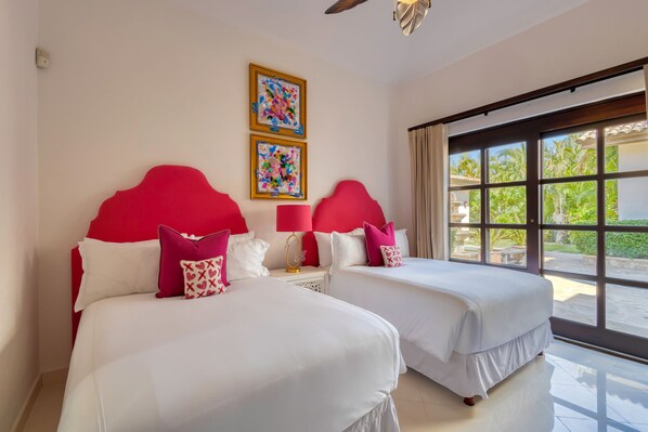 A hotel room with two beds, a large window with a view of greenery, and two framed artworks on the wall. - Escape to Paradise in Cabo San Lucas! (Cabo San Lucas)