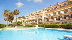 A hotel with a swimming pool, palm trees, and a clear blue sky. - Studio in Marbella Beachfront With Pool (Marbella)