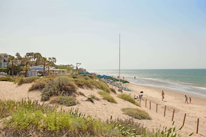 A beach with sand dunes, beach umbrellas, and a few people. - Studio in Marbella Beachfront With Pool (Marbella)