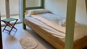 A bunk bed with a wooden frame and white bedding, a small stool, and a round rug on a tiled floor. - Domus Aurus Family, Domus Aurus Family  (Bardolino)