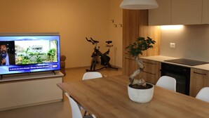 A modern kitchen with a TV, wooden table, and a potted plant. - Domus Aurus Family, Domus Aurus Family  (Bardolino)
