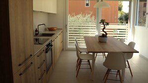 A modern kitchen with wooden cabinets, a dining table with chairs, and a view of a balcony with a railing. - Domus Aurus Family, Domus Aurus Family  (Bardolino)