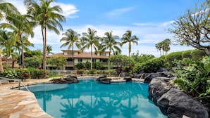 A pool surrounded by palm trees and a building with a tiled roof. - Waikoloa Beach Villas F32 (Waikoloa)