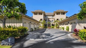 A residential building with a central entrance, multiple garage doors, and a landscaped driveway. - Waikoloa Beach Villas F32 (Waikoloa)