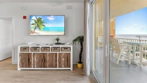 Una habitación con una televisión con temática de playa, un mueble de madera con cestas y una planta en maceta.