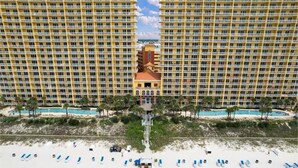 Un hotel de gran altura con varios balcones, un edificio central de diseño arquitectónico único y una zona de playa con tumbonas.