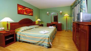 Una camera d'albergo con un letto, abat-jour, televisore, uno specchio e un quadro appeso al muro.