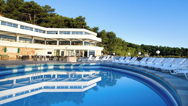 A swimming pool with sun loungers and a building with multiple balconies. - Fontana Bayside Park (Jelsa)