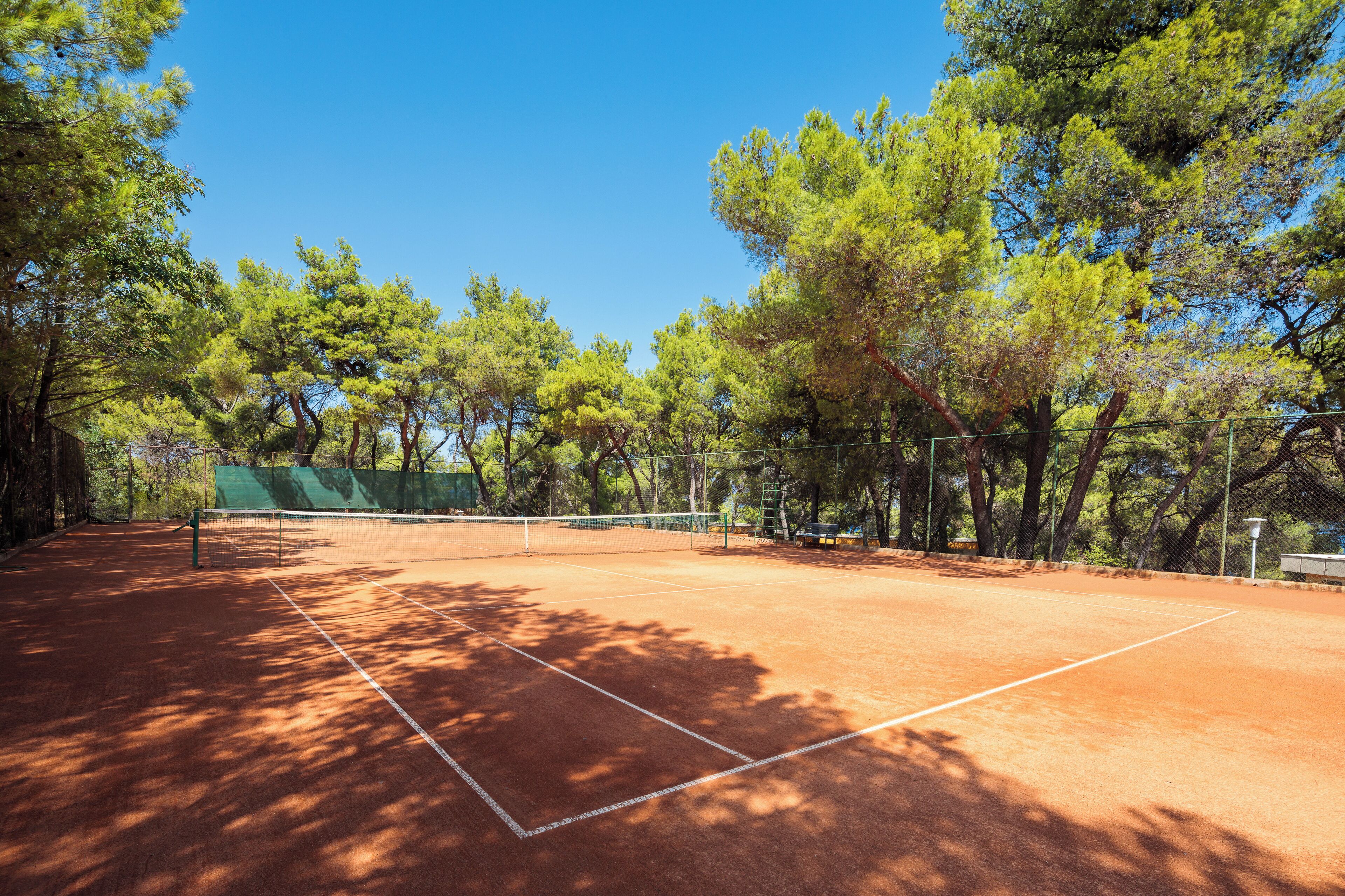 Una cancha de tenis rodeada de árboles.