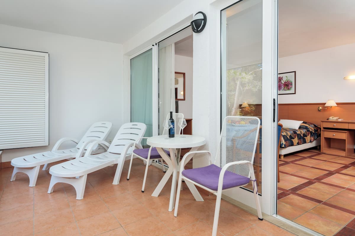 Un balcone con poltrone bianche, un tavolino e una sedia con cuscino viola.
