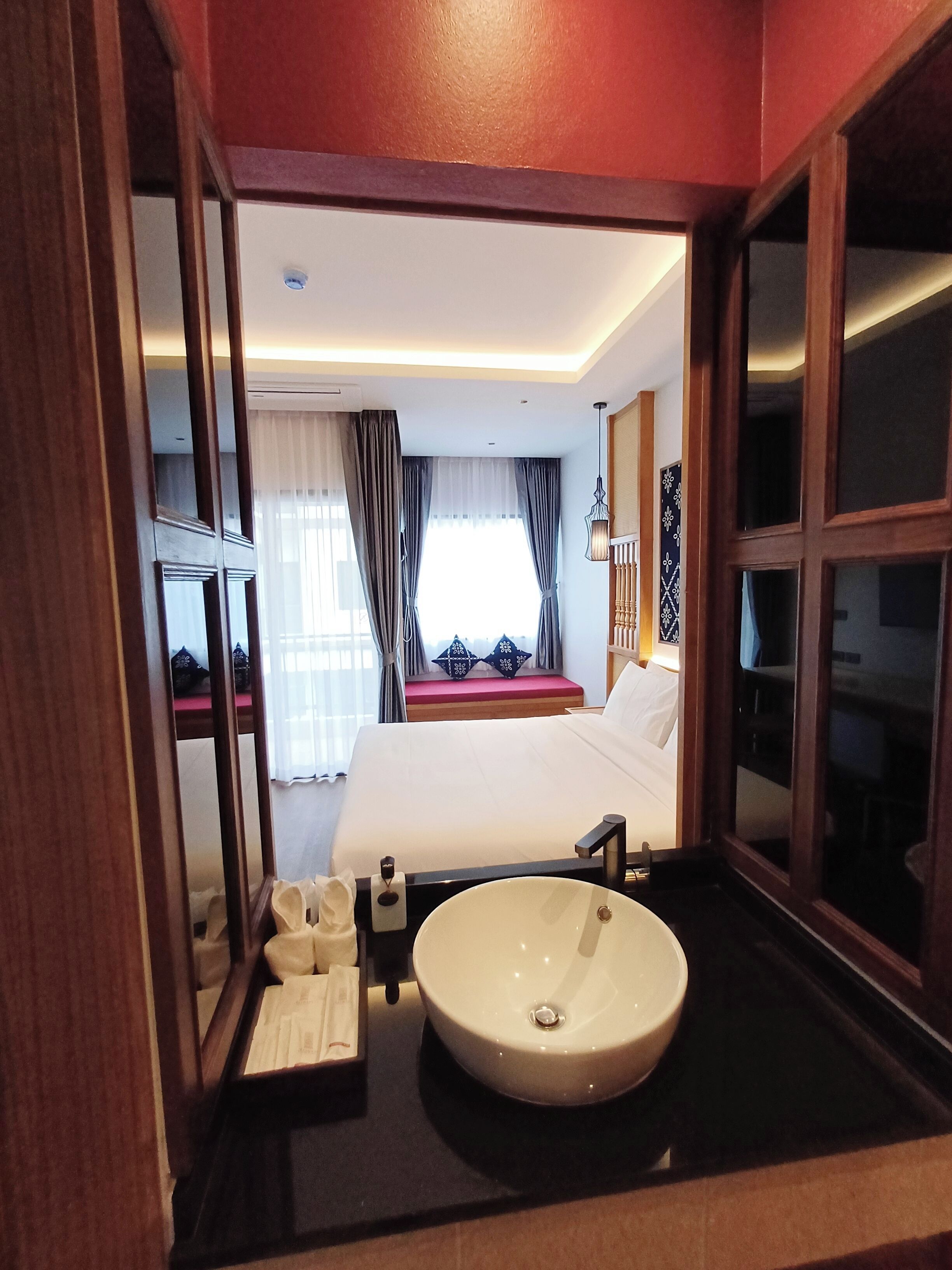 Una camera d'albergo con un letto grande, un comodino con un lavandino e uno specchio.