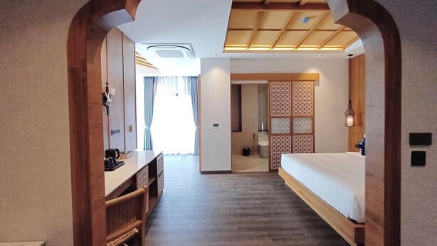 Habitación de hotel con escritorio de madera, cama, baño y vistas al exterior.