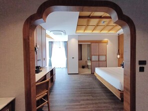 Ein Hotelzimmer mit einem hölzernen Schreibtisch, einem Bett, einem Badezimmer und Blick ins Freie.