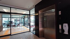 Un ascensor moderno con detalles metálicos, puerta de vidrio y dispensador de gel antibacterial.