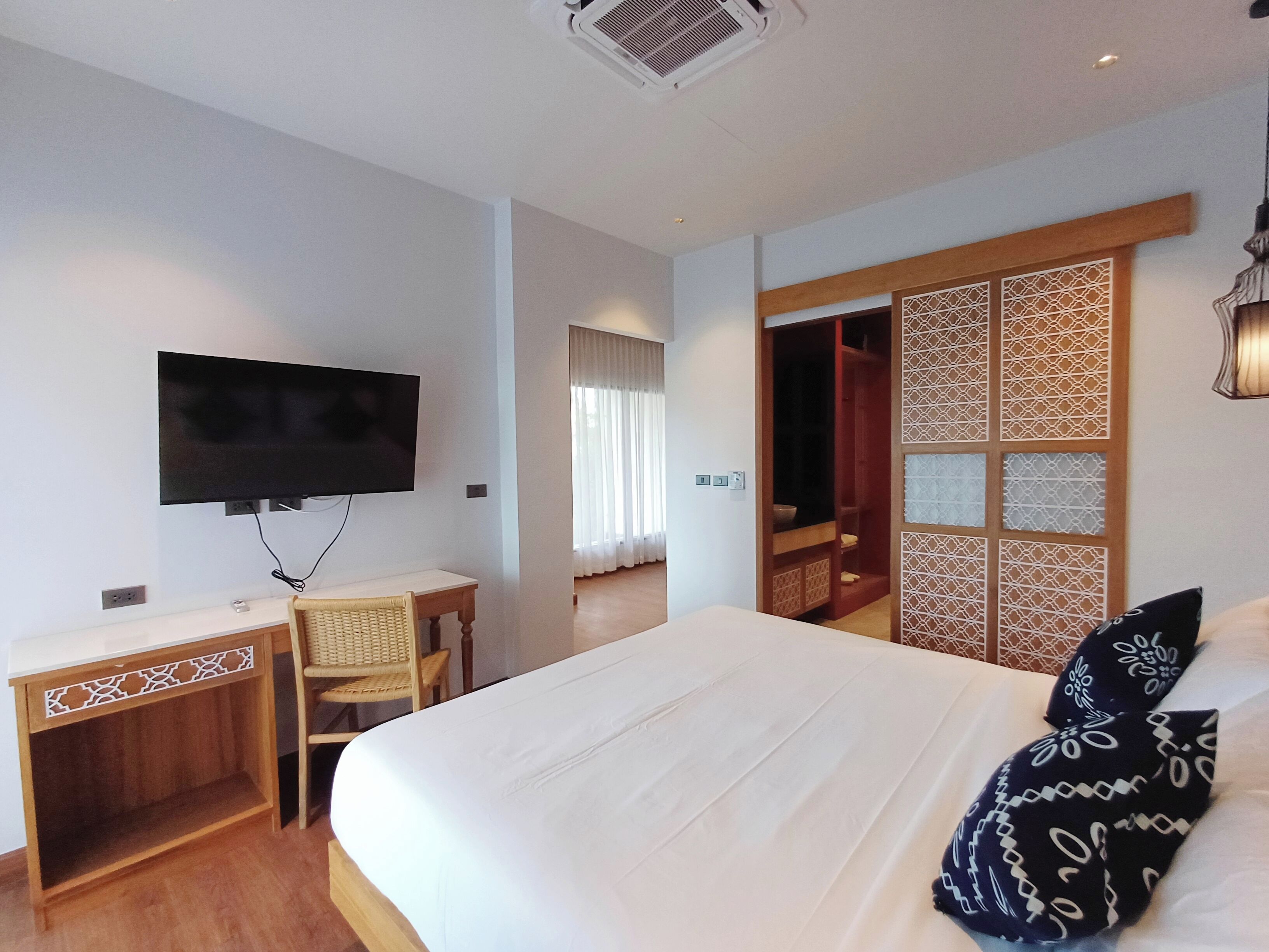 A hotel room with a bed, a TV mounted on the wall, a desk, and a chair.