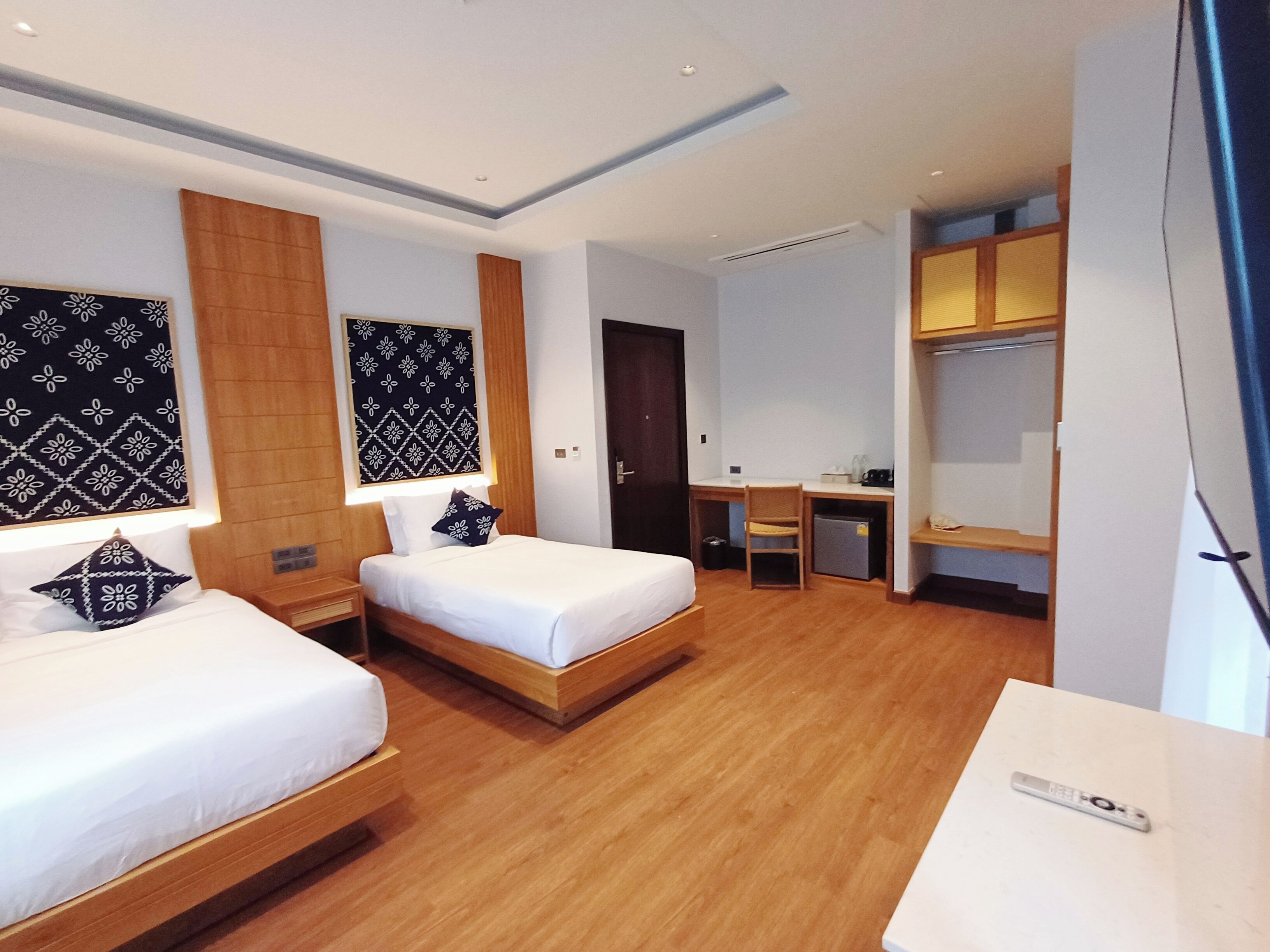 A hotel room with two single beds, a desk, a chair, and a wardrobe.