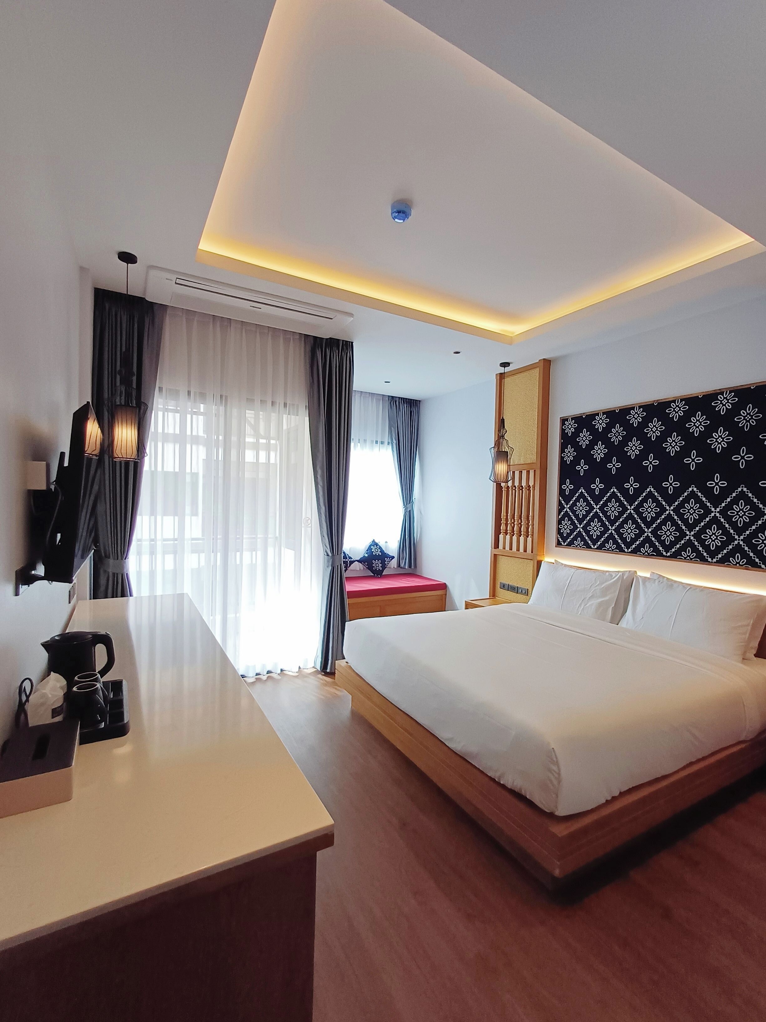Une chambre d’hôtel moderne avec un grand lit, une table de chevet et un bureau équipé d’une machine à café.