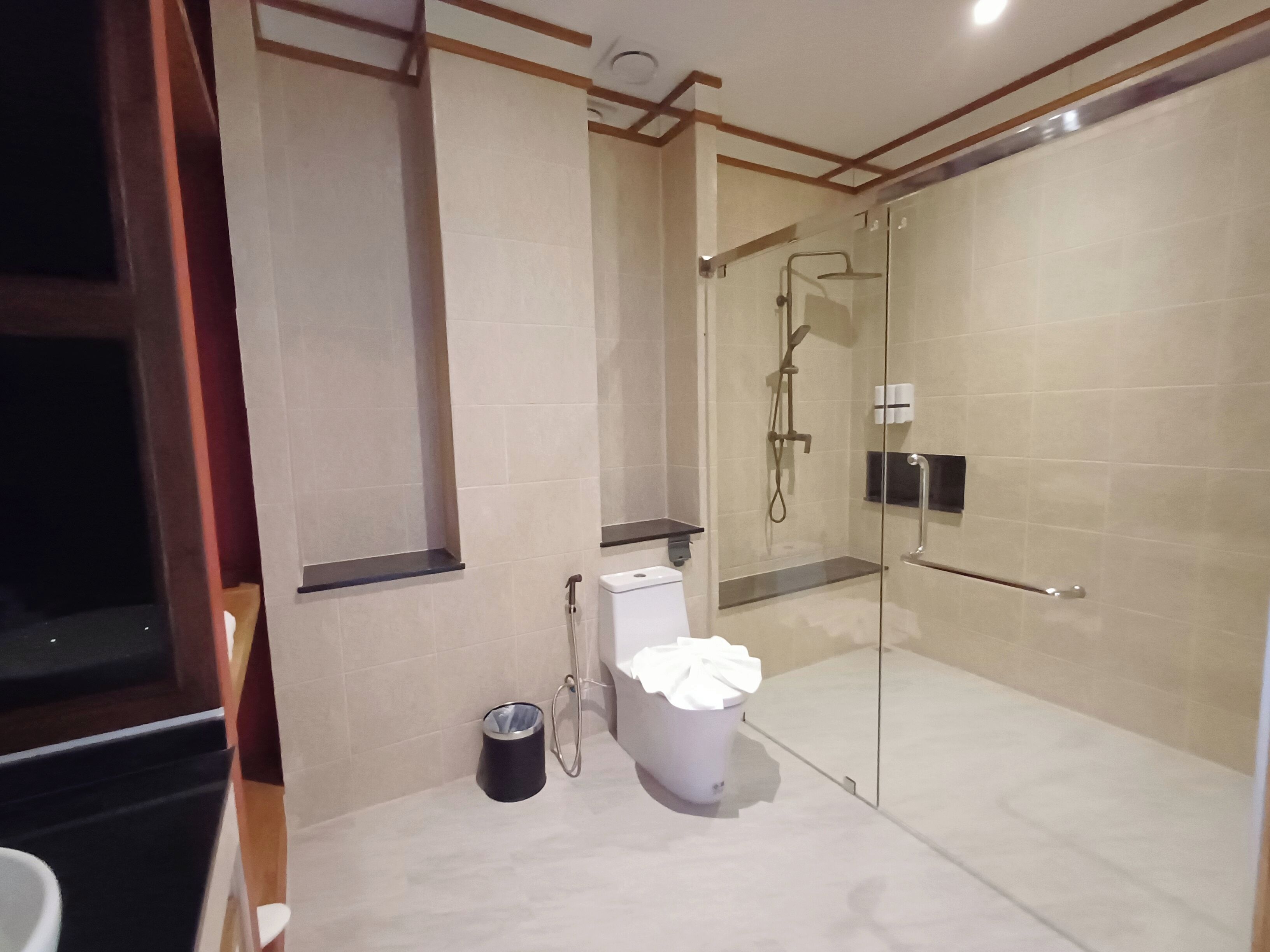 Un baño moderno con ducha de vidrio, inodoro y cubo de basura.