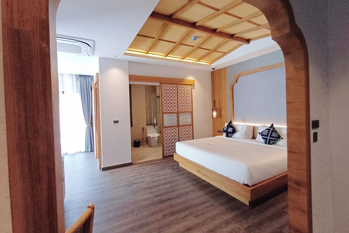 Ein modernes Hotelzimmer mit einem hölzernen Bett, einem großen Fenster und einer traditionellen japanischen Schiebetür.