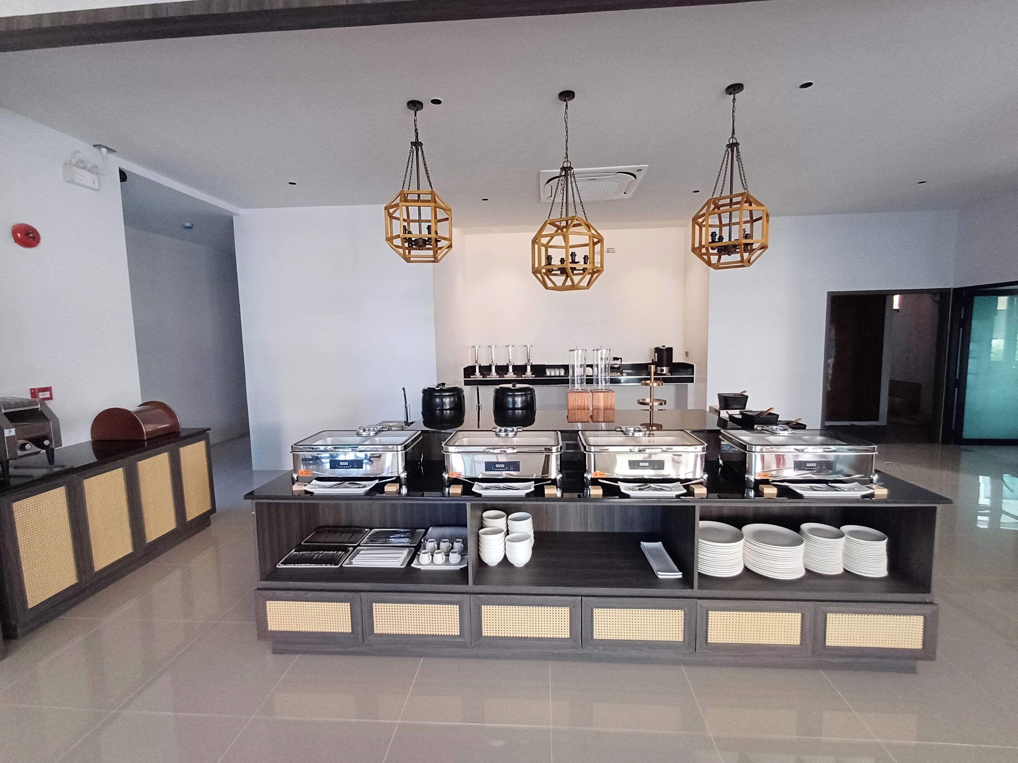 A buffet setup with various food containers and utensils, a coffee machine, and decorative lighting.
