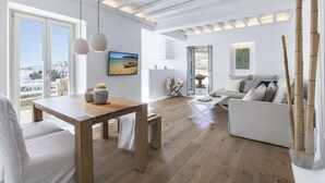 Un salon spacieux avec une table à manger en bois, un canapé et une vue sur la ville grâce à de grandes fenêtres.