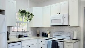 A modern kitchen with white cabinetry, a built-in microwave, a stove, and a refrigerator.