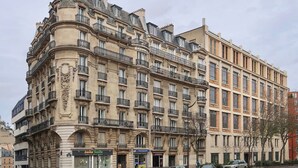 A multi-story building with a classical architectural style, featuring ornate balconies and a corner turret. - A BLEND OF MINIMALIST ELEGANCE, PARISIAN FLAIR NEAR RUE MOUFFETARD-LATIN QUARTER (Paris)