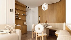 A modern living room with a sofa, a dining table with chairs, and a wooden cabinet with shelves. - A BLEND OF MINIMALIST ELEGANCE, PARISIAN FLAIR NEAR RUE MOUFFETARD-LATIN QUARTER (Paris)