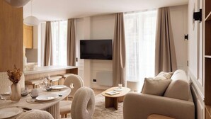 A modern hotel room with a dining area, a flat-screen TV, and a comfortable seating arrangement. - A BLEND OF MINIMALIST ELEGANCE, PARISIAN FLAIR NEAR RUE MOUFFETARD-LATIN QUARTER (Paris)