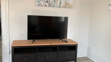 A wooden TV stand with a flat-screen TV, three drawers, and a remote control on top.