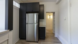 Een moderne keuken met donkere kastjes, een roestvrijstalen koelkast en een lichtkleurig aanrecht.