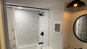 Een badkamer met douche, toilet en wastafel.