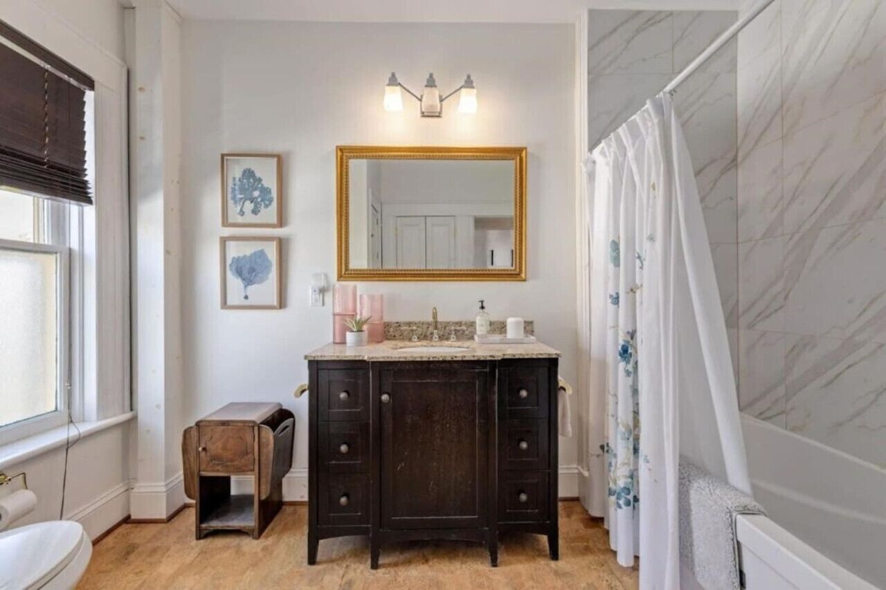 Een badkamer met een donker houten wastafelmeubel, een grote spiegel en een douchegordijn.