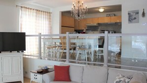 A living room with a sofa, a television, and a dining area with chairs and a table. - Family Friendly in Picton, PEC! (Prince Edward)