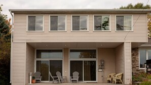 A two-story building with a flat roof, large windows, and a covered front porch with chairs. - Family Friendly in Picton, PEC! (Prince Edward)